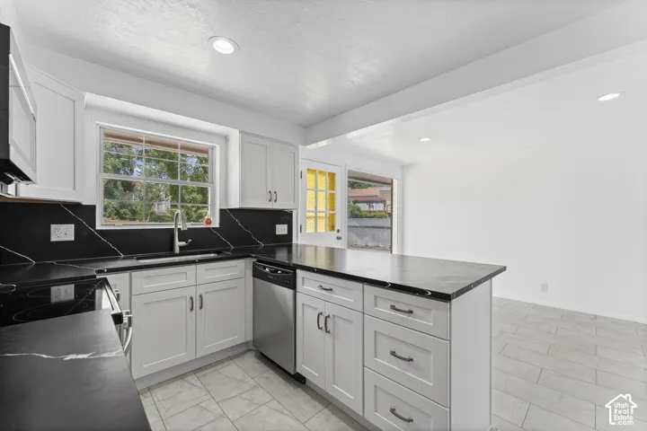 Kitchen featuring white shaker cabinetry, black countertops with white veining, stainless steel appliances, and a central island