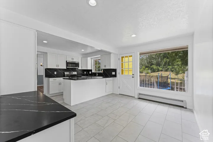 Spacious kitchen with white cabinetry, dark quartz countertops, and a full suite of stainless steel appliances