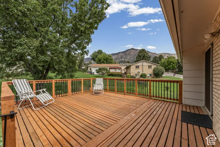 Expansive wood deck with black metal railing, offering a mountain backdrop and mature trees