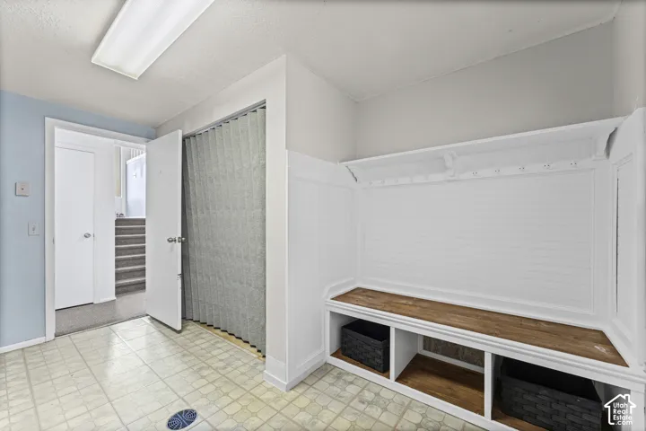 Built-in storage bench with wood-finish top and lower cubbies, beadboard backing, and coat hooks