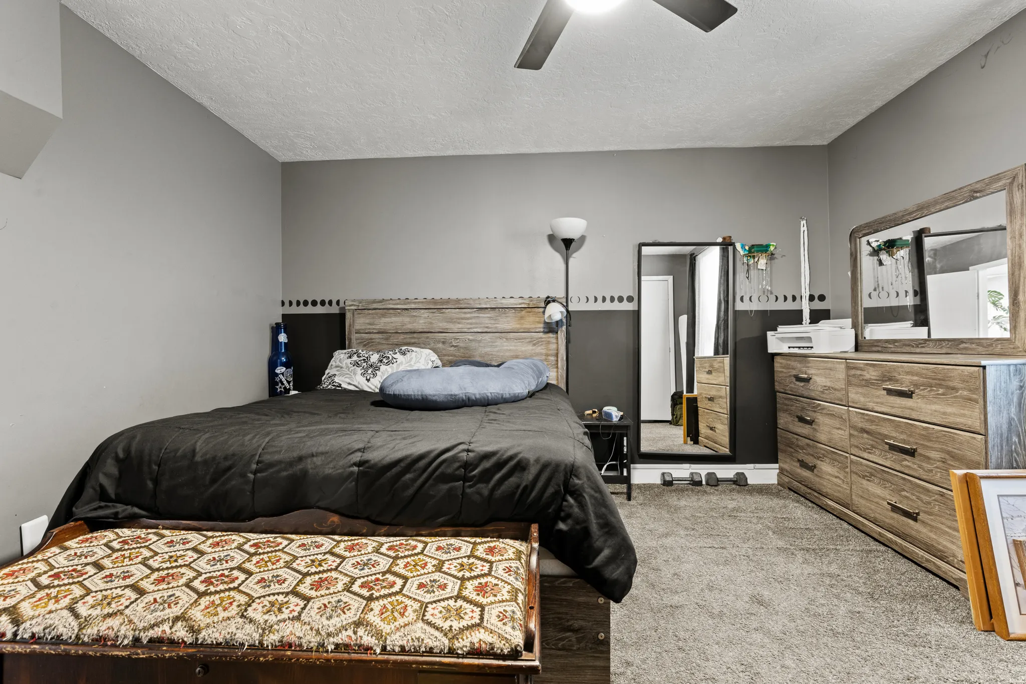 Bedroom featuring a wood-finish headboard, gray carpeting, and a ceiling fan
