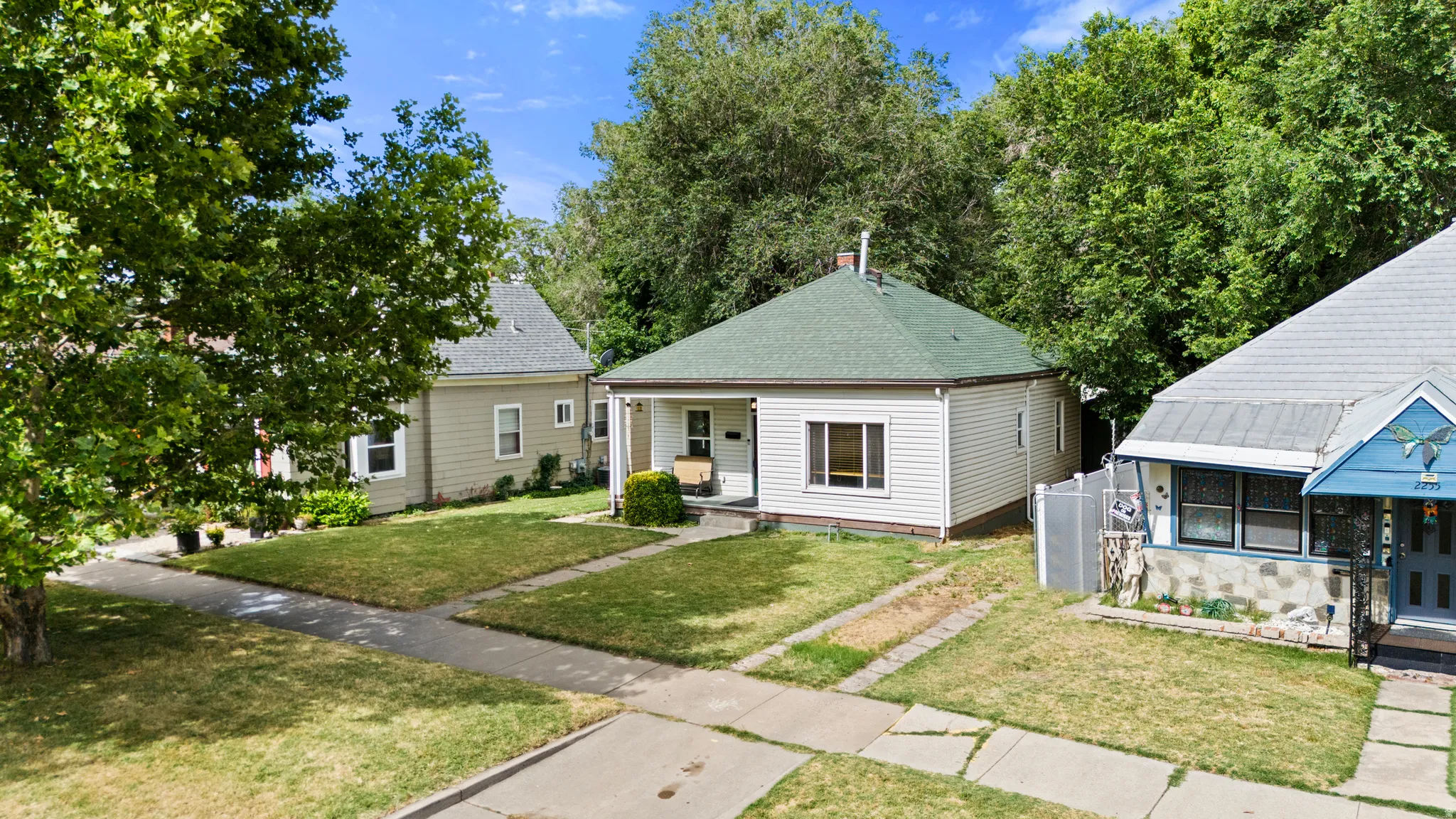 White-sided residence with a green shingled roof and front porch