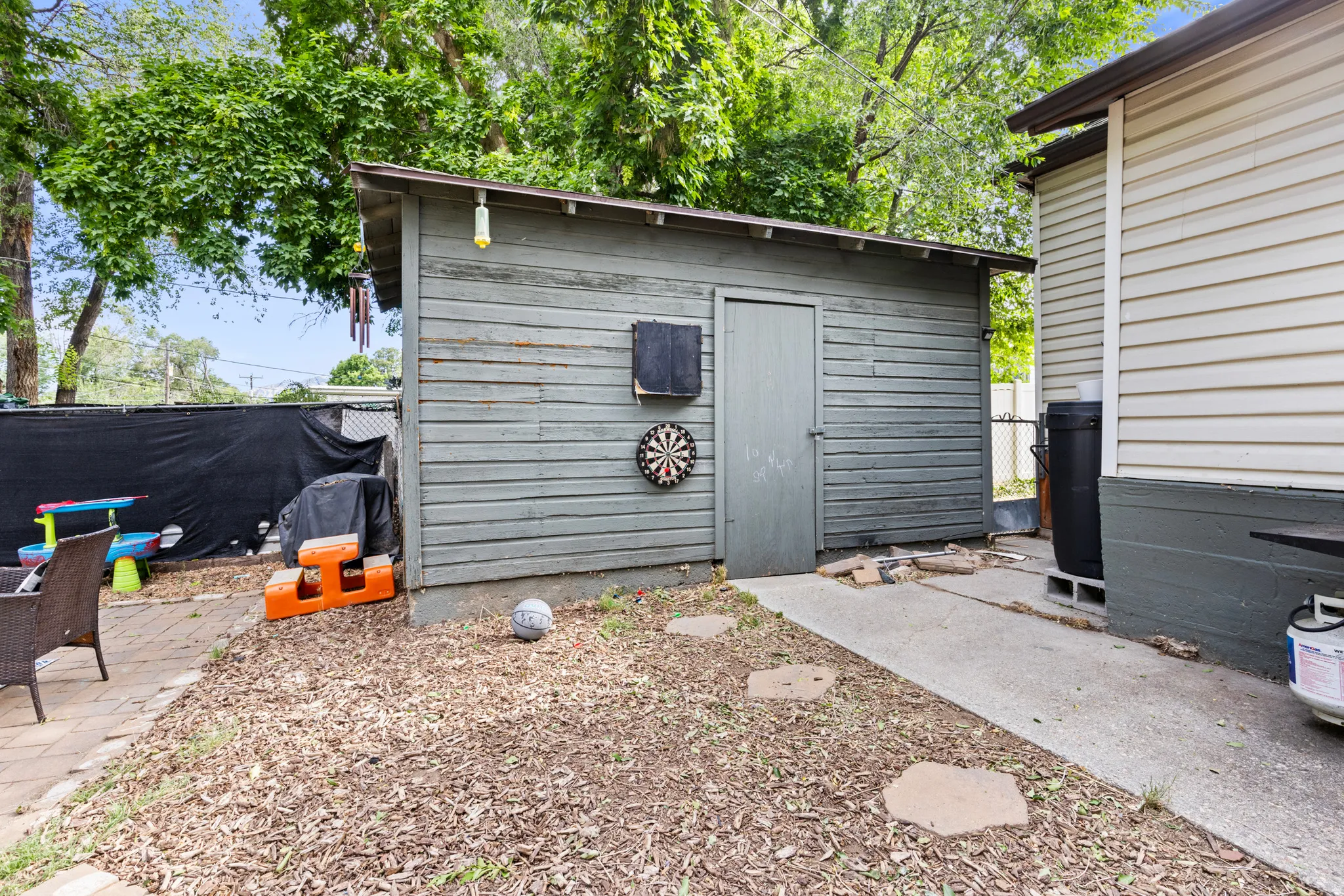 Detached shed with horizontal wood siding, asphalt shingle roof, and a single entry door