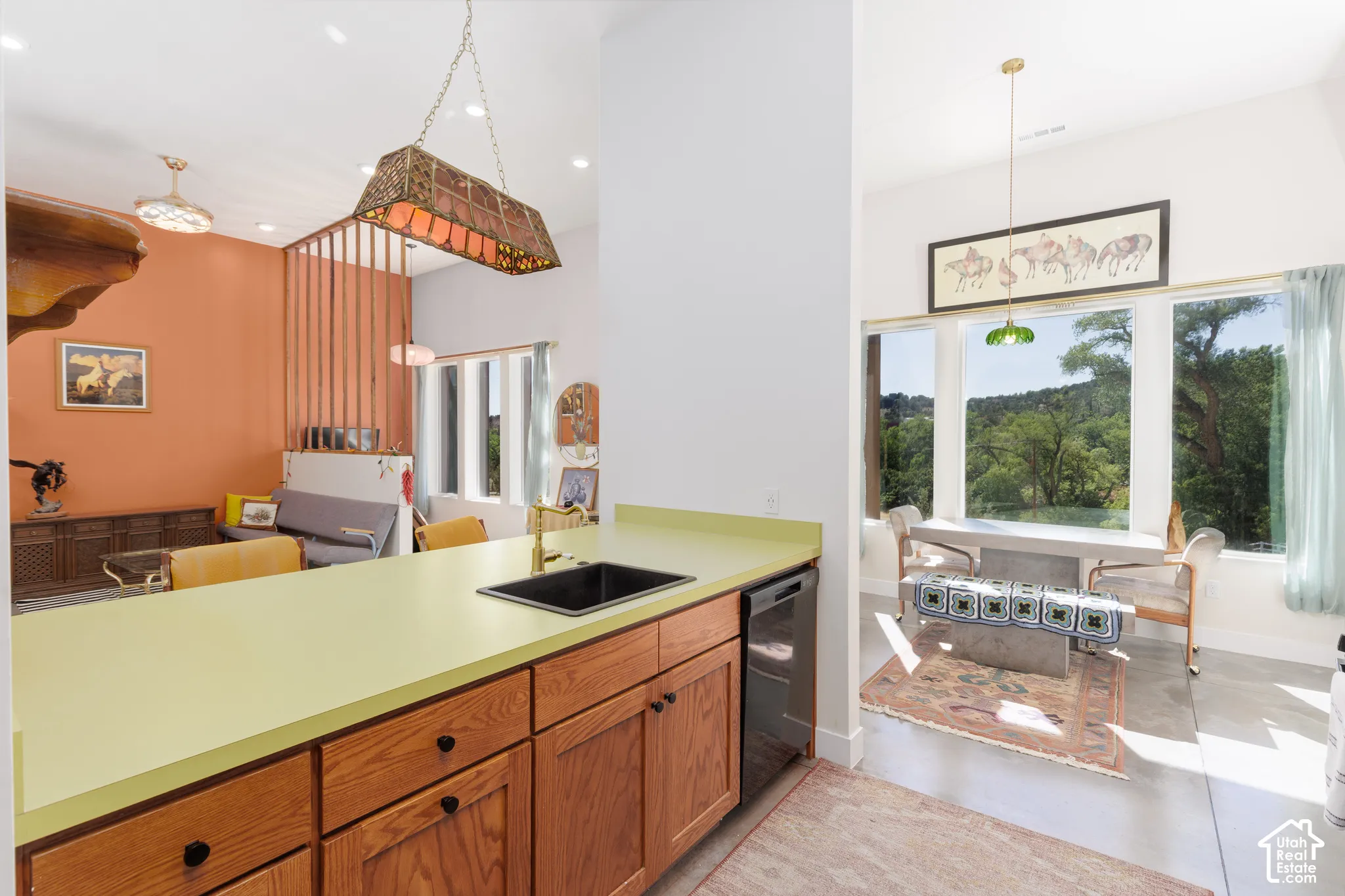 Kitchen island with light green countertop, black sink, and wood cabinetry