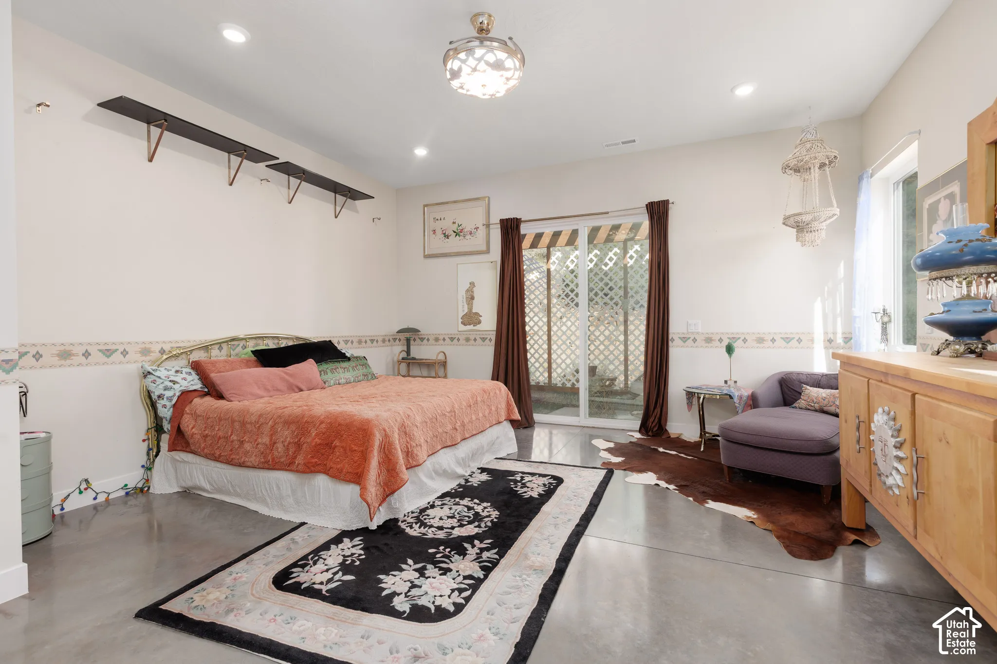 Bedroom featuring polished concrete flooring, a sliding glass door with lattice detailing, recessed ceiling lighting, and a decorative ceiling light fixture