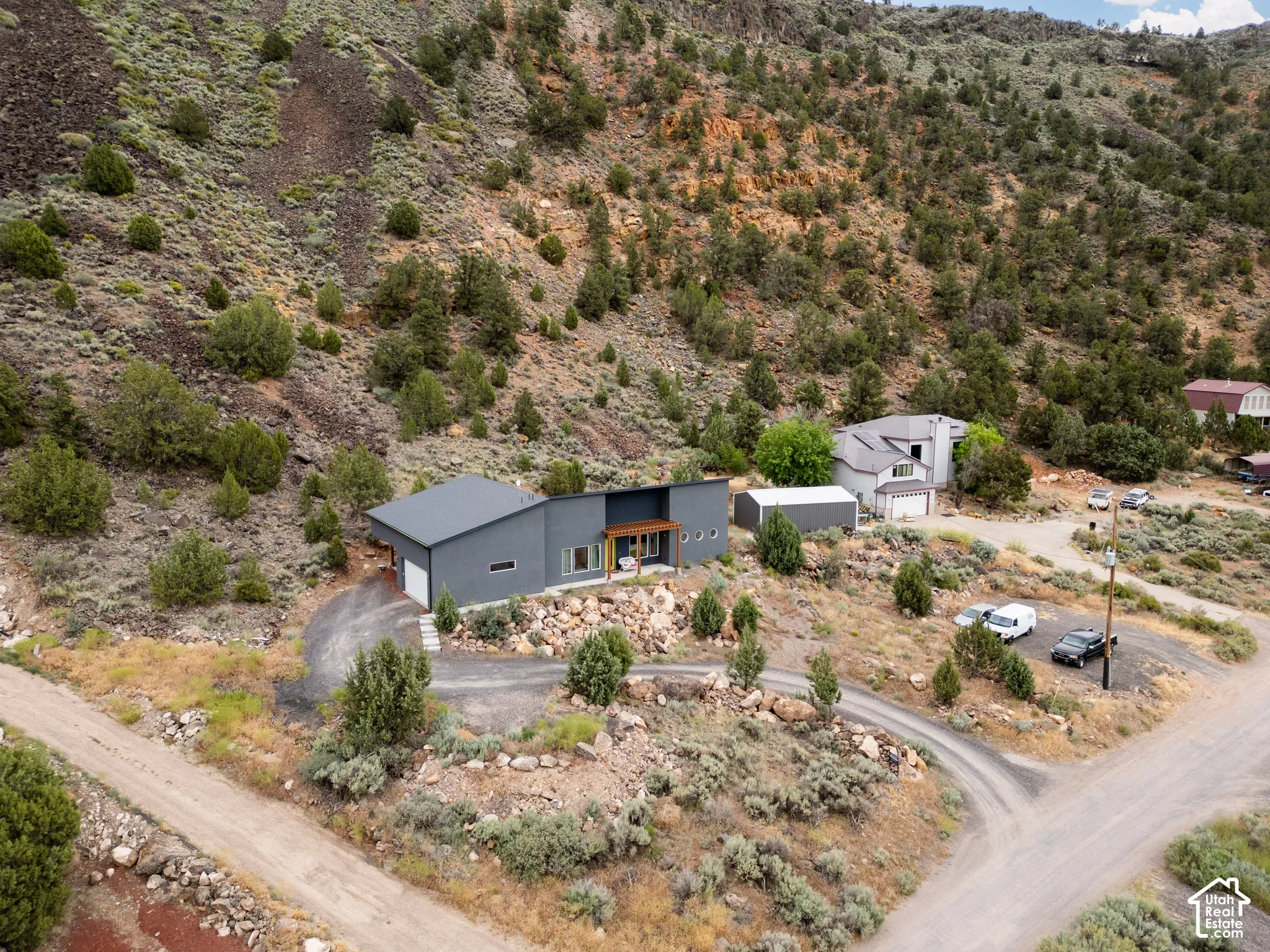 Modern gray exterior architecture featuring a dark roof, attached garage, and a gravel driveway