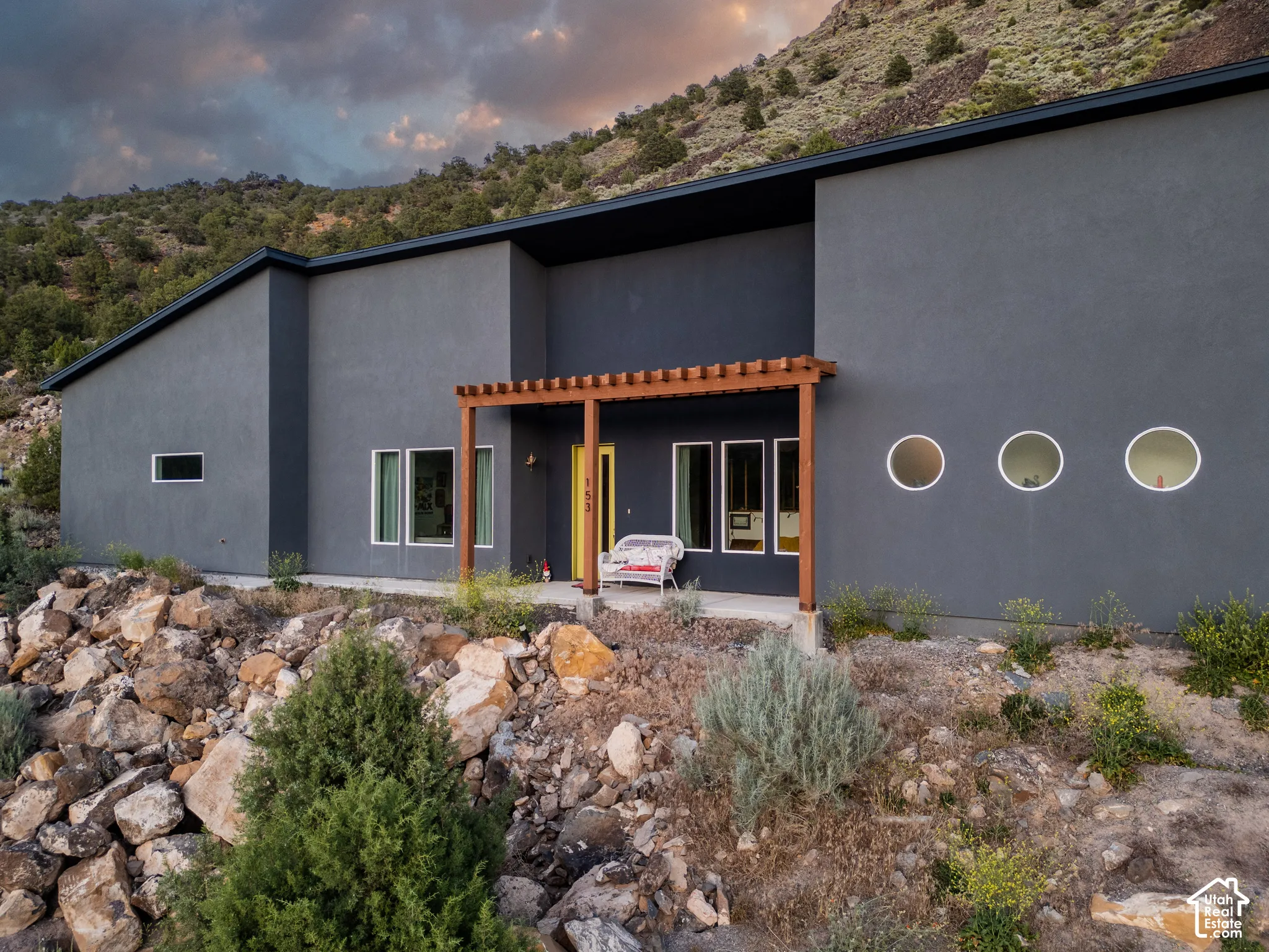Contemporary exterior featuring a charcoal-hued facade, a flat roofline, and a prominent wood pergola entry