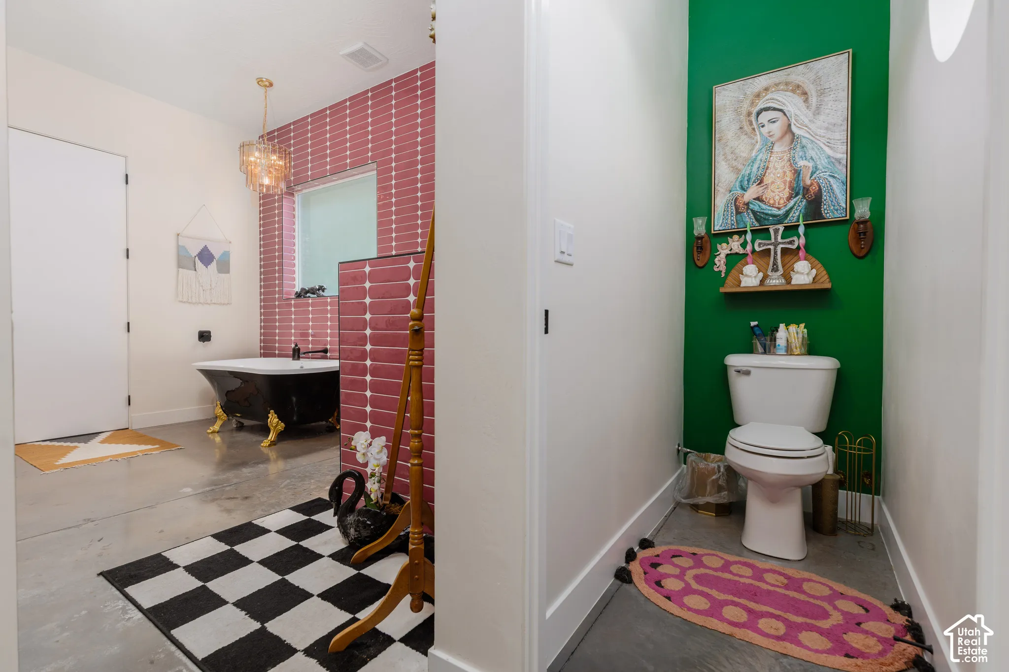 Spacious bathroom featuring a black clawfoot tub with gold-tone feet, a tiled accent wall, and a unique chandelier