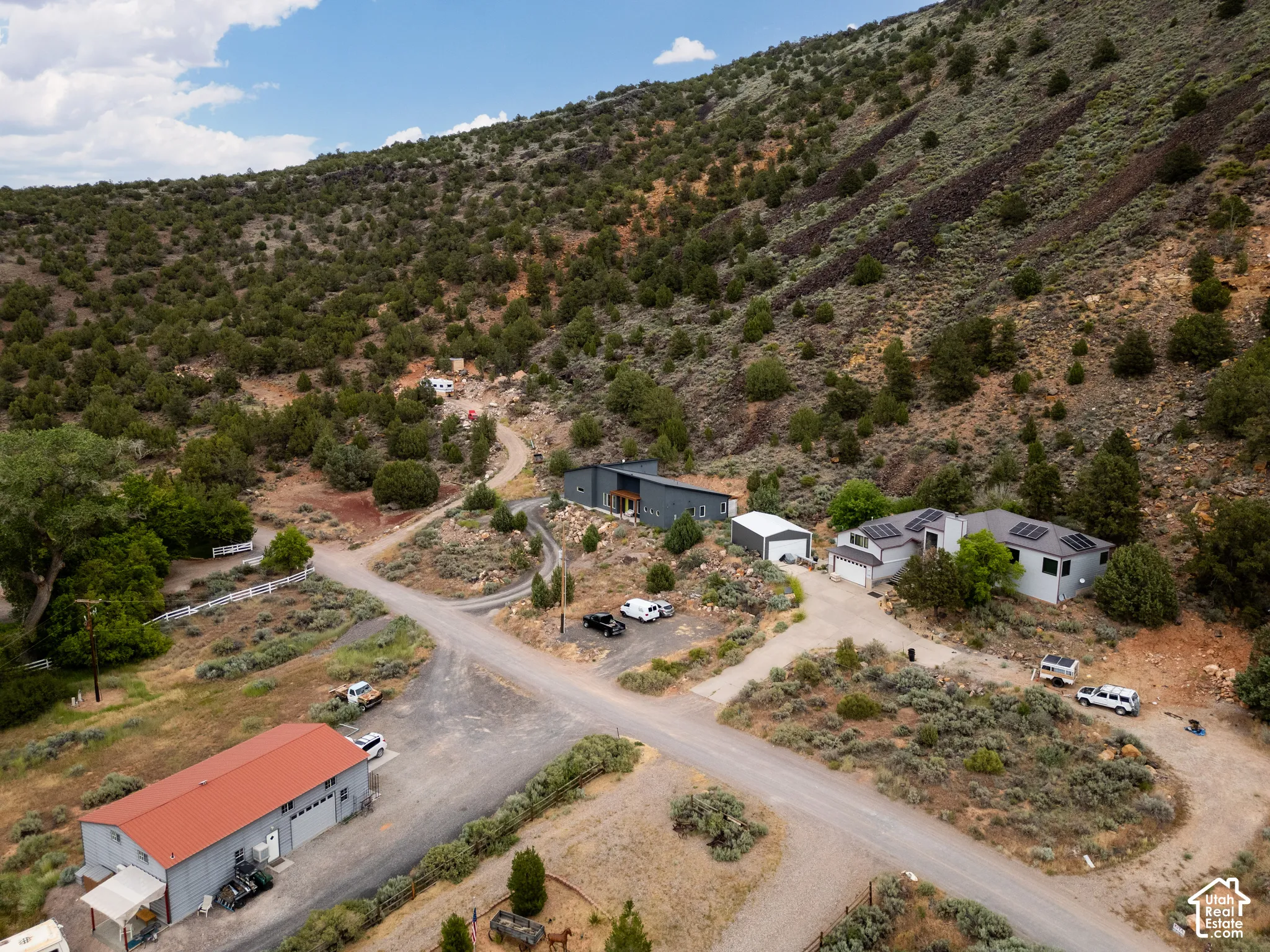 Multiple structures situated on a sloped, natural landscape with mature vegetation