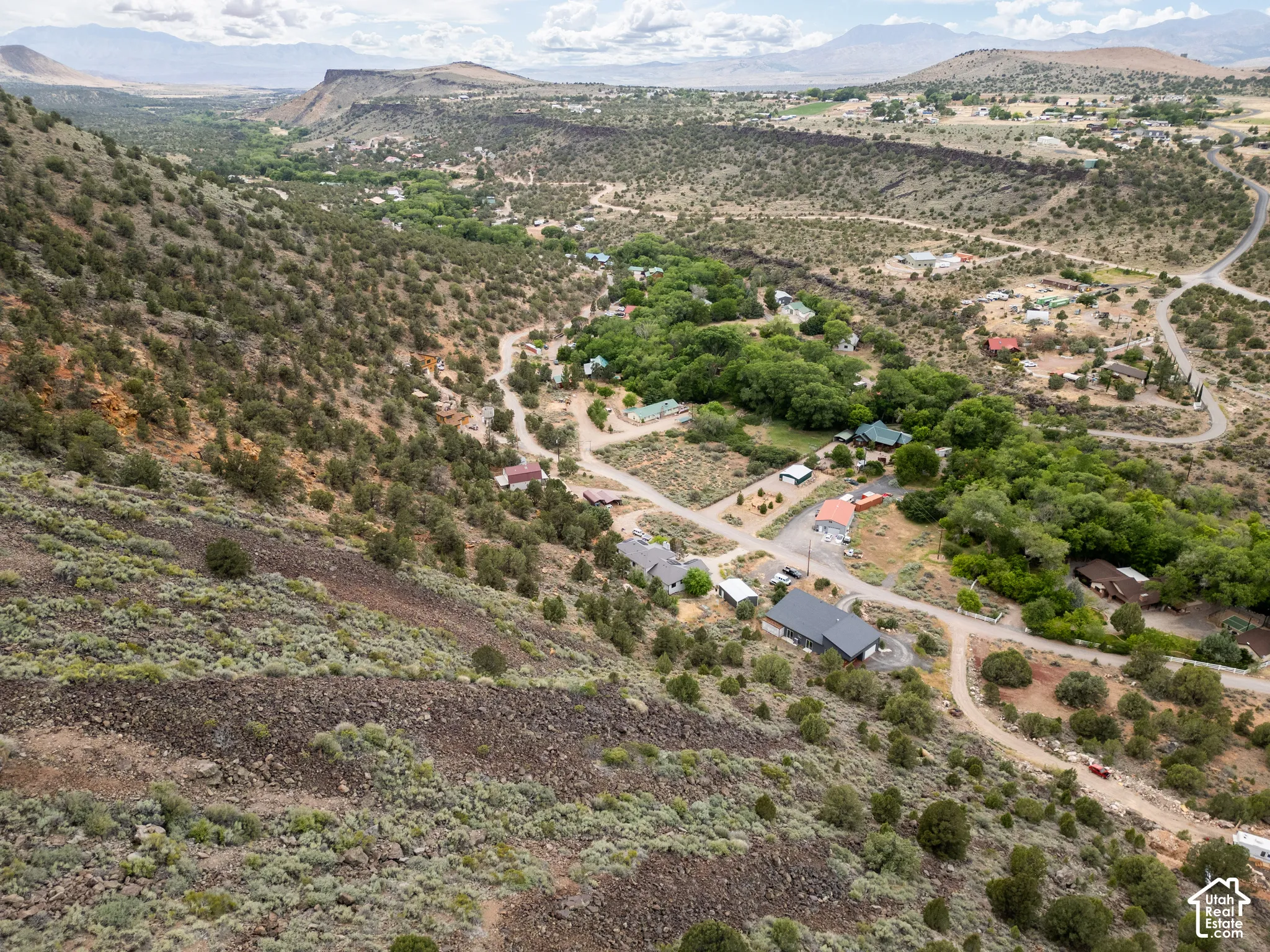Mountainous terrain featuring diverse vegetation, residential structures, and winding roads