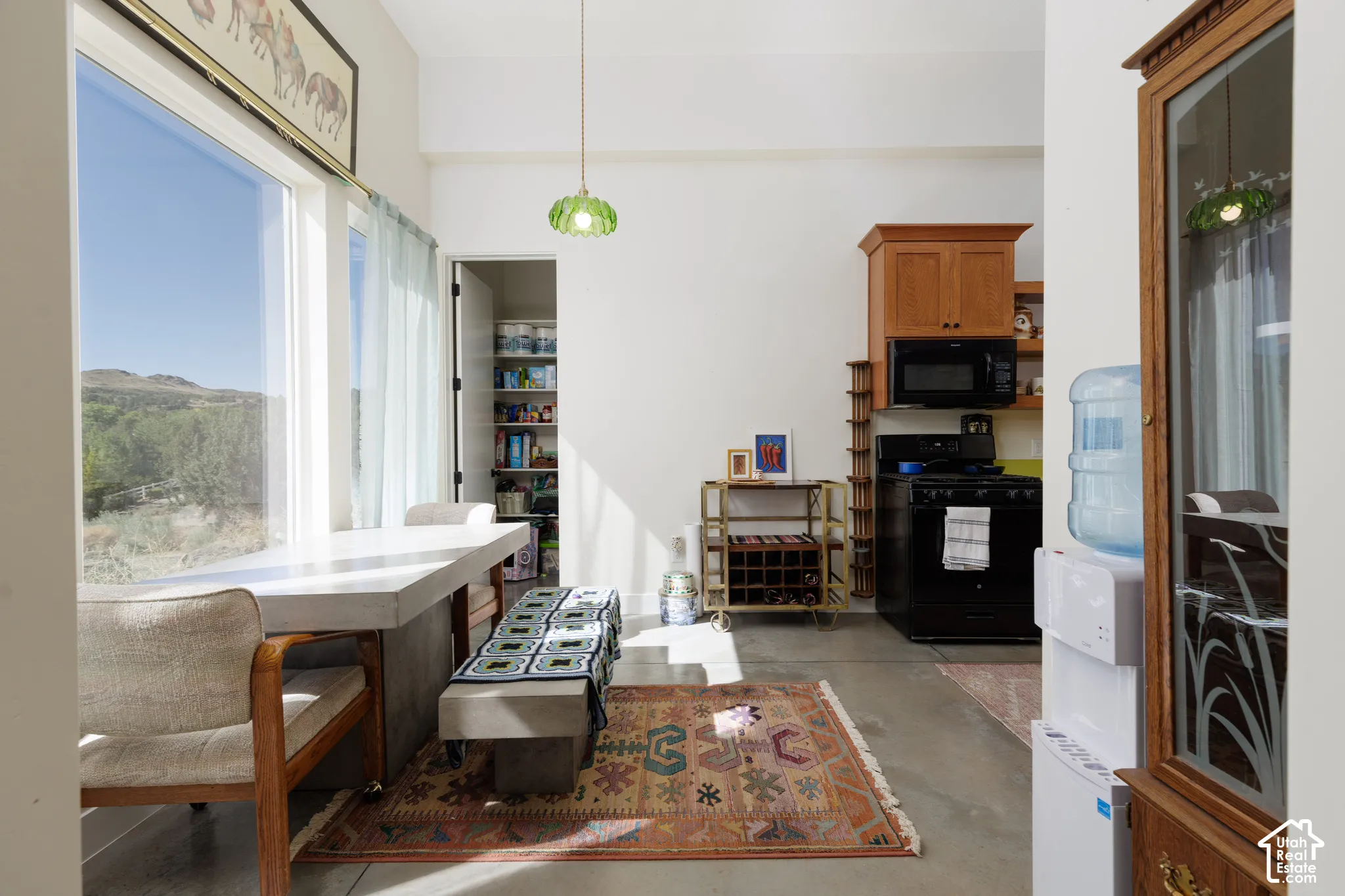 Spacious dining area featuring a large window, concrete-finish dining table, and direct access to a pantry