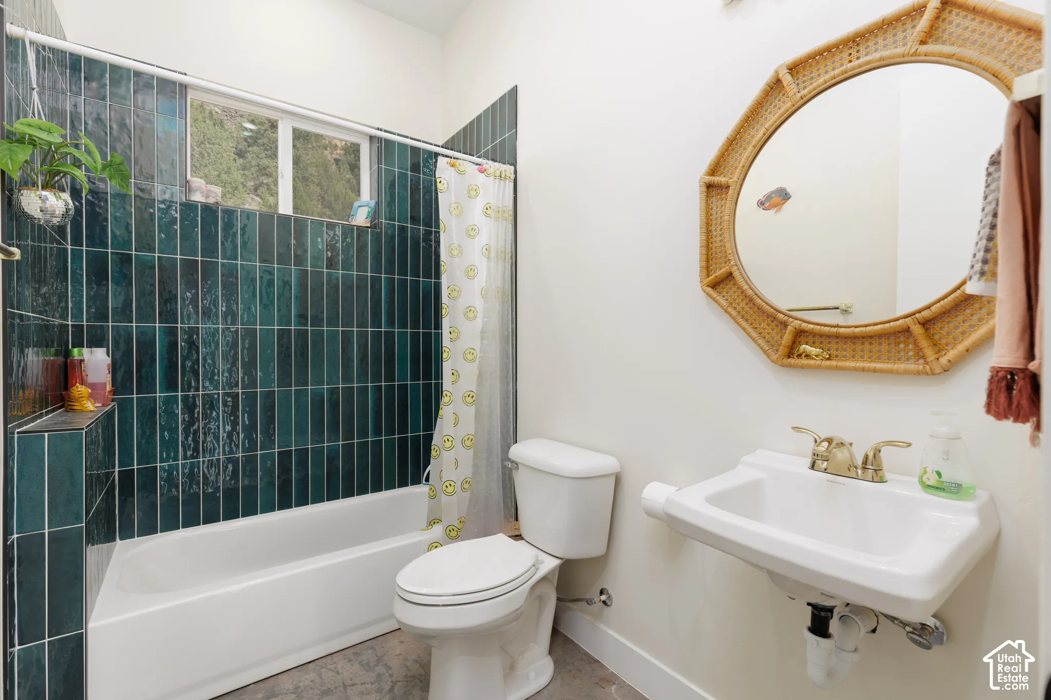 Bathroom featuring a white bathtub, dark green vertical tile surround, a built-in shower niche, and a window