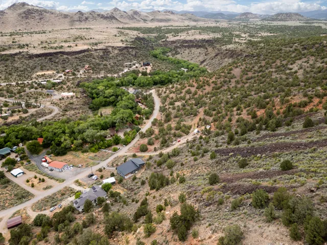 Expansive aerial view of a desert landscape featuring winding roads, scattered residential structures, and a lush green riparian area