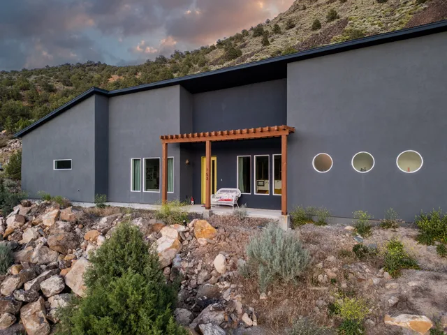 Contemporary exterior featuring a charcoal-hued facade, a flat roofline, and a prominent wood pergola entry