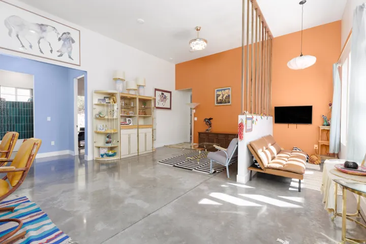 Polished concrete flooring extending throughout, complemented by a partial wood slat partition and a vaulted ceiling