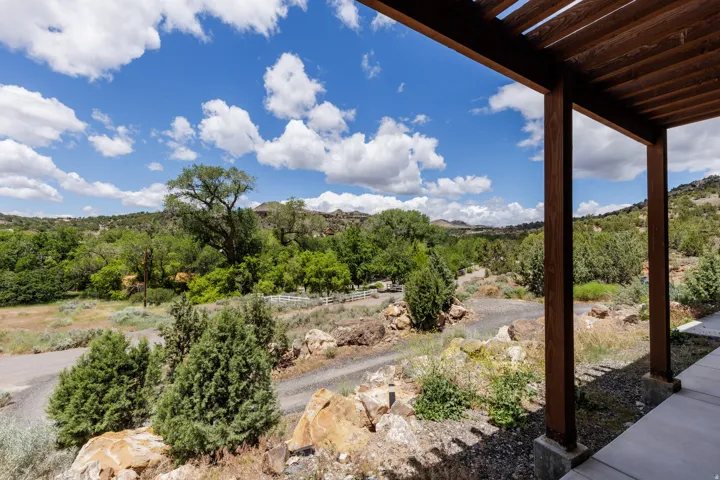 Expansive exterior setting featuring a distant mountain backdrop, mature trees, natural rock formations, and a white fence line