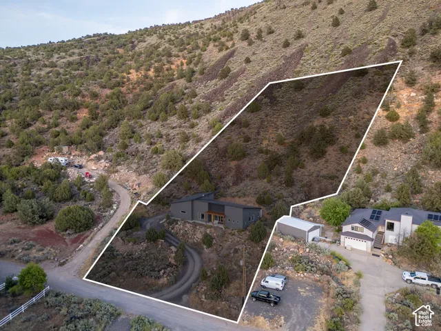 Modern residence with a dark facade and wood-paneled accents, nestled into a natural hillside setting