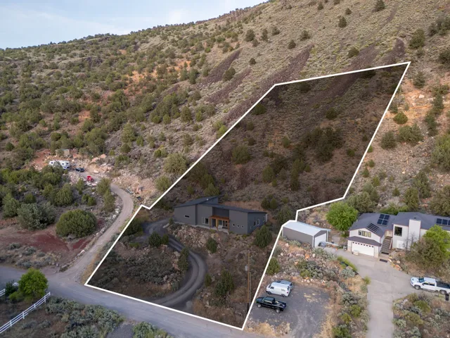 Modern residence with a dark facade and wood-paneled accents, nestled into a natural hillside setting