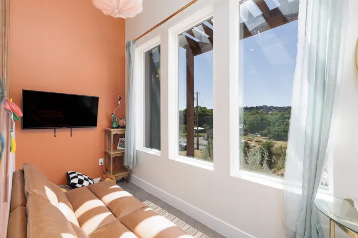 Room featuring a wall-mounted television, a distinct accent wall, and high ceilings