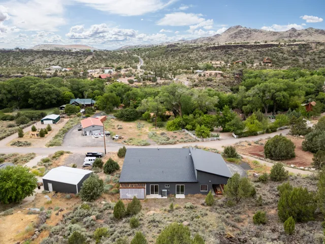 Contemporary residence featuring a dark gray exterior, a shed roof, and multiple outbuildings
