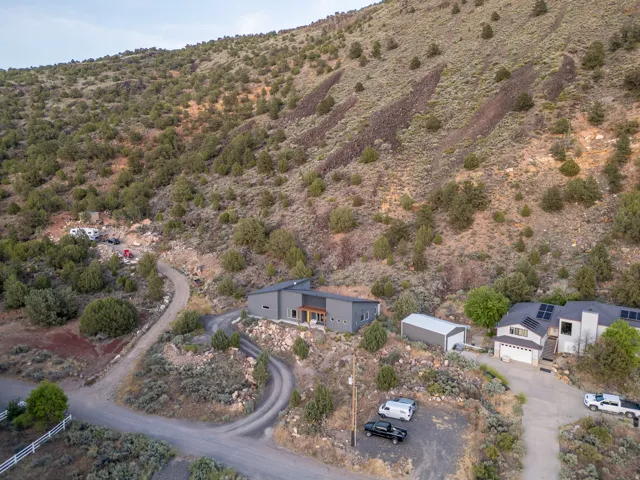 Modern dwelling nestled into a natural hillside with a winding gravel driveway