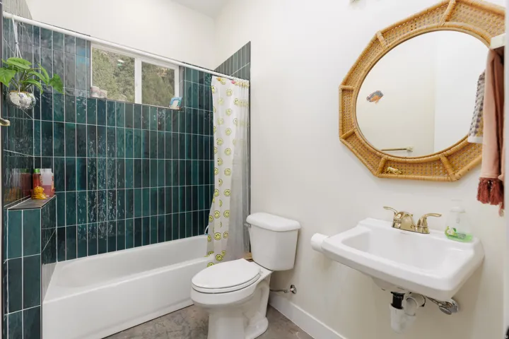 Bathroom featuring a white bathtub, dark green vertical tile surround, a built-in shower niche, and a window