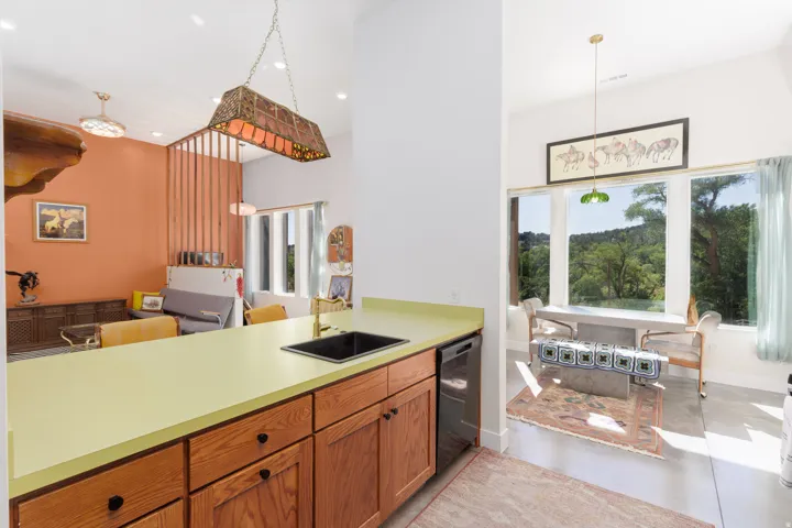 Kitchen island with light green countertop, black sink, and wood cabinetry