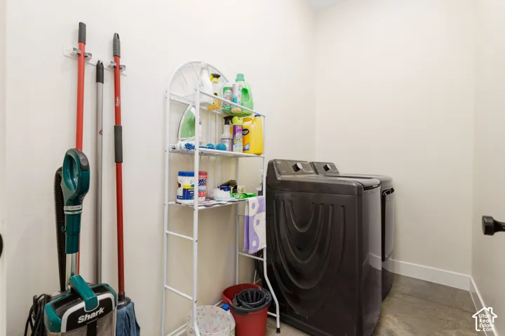 Dedicated laundry area featuring a washer and dryer, finished walls, and durable flooring