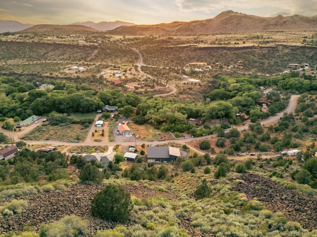 Expansive natural landscape with varied topography featuring distant mountains, established foliage, and multiple residential structures