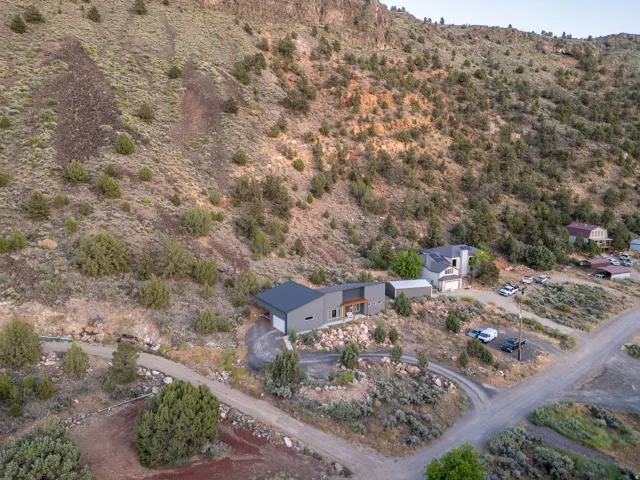 Contemporary gray exterior featuring a dark roof, attached garage, and a gravel driveway