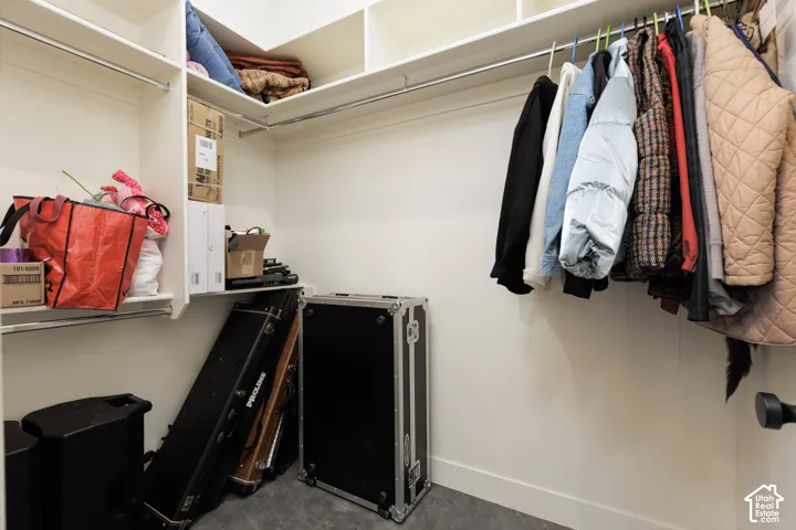 Walk-in closet featuring white shelving, multiple hanging rods, and a neutral wall color
