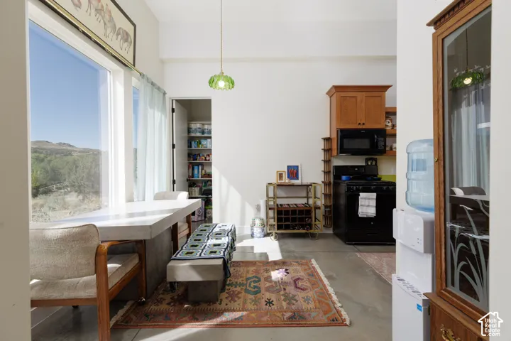 Spacious dining area featuring a large window, concrete-finish dining table, and direct access to a pantry