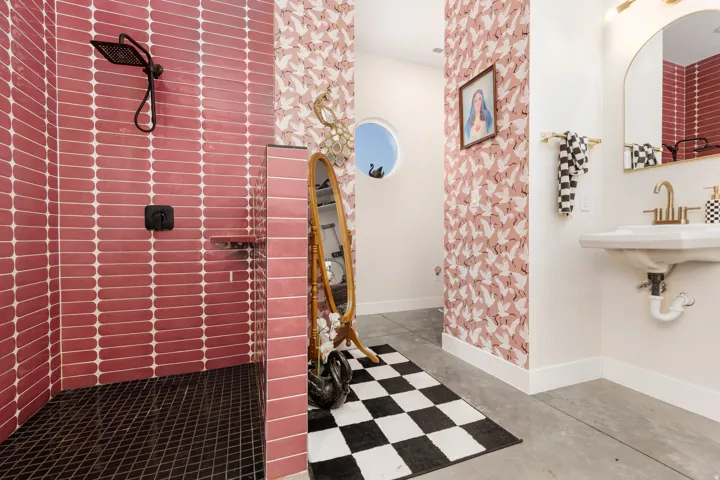 Walk-in shower with vertical pink tiled walls and dark square floor tiles