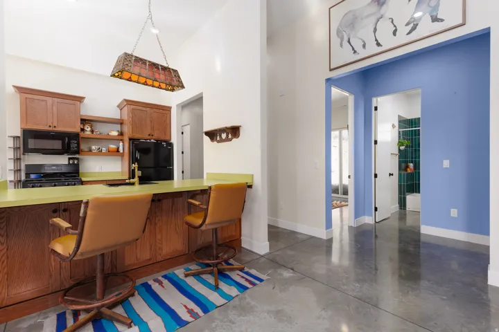 Kitchen area featuring a wood-finish breakfast bar with lime green countertop, upper and lower cabinetry, and black appliances