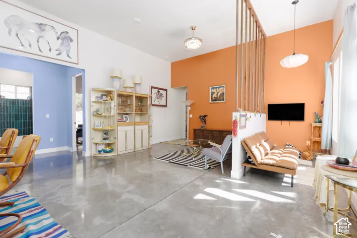 Polished concrete flooring extending throughout, complemented by a partial wood slat partition and a vaulted ceiling