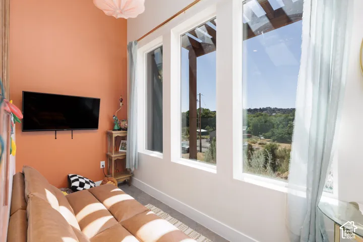 Room featuring a wall-mounted television, a distinct accent wall, and high ceilings
