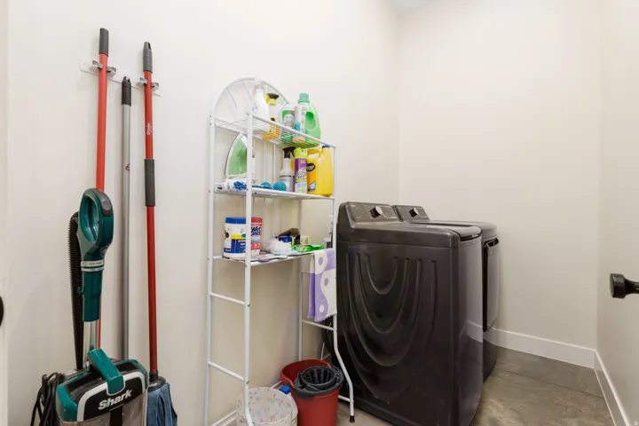 Dedicated laundry area featuring a washer and dryer, finished walls, and durable flooring