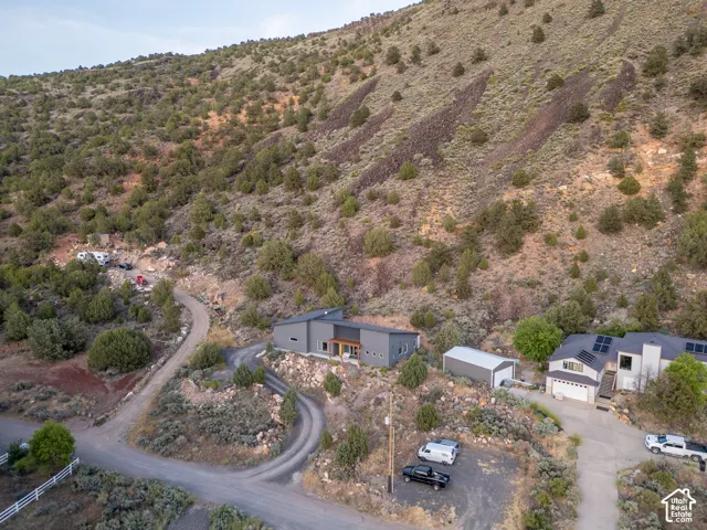 Modern dwelling nestled into a natural hillside with a winding gravel driveway