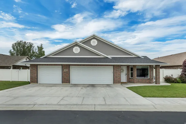 Brick and siding exterior featuring a multi-car driveway, two garage doors, and a covered entryway