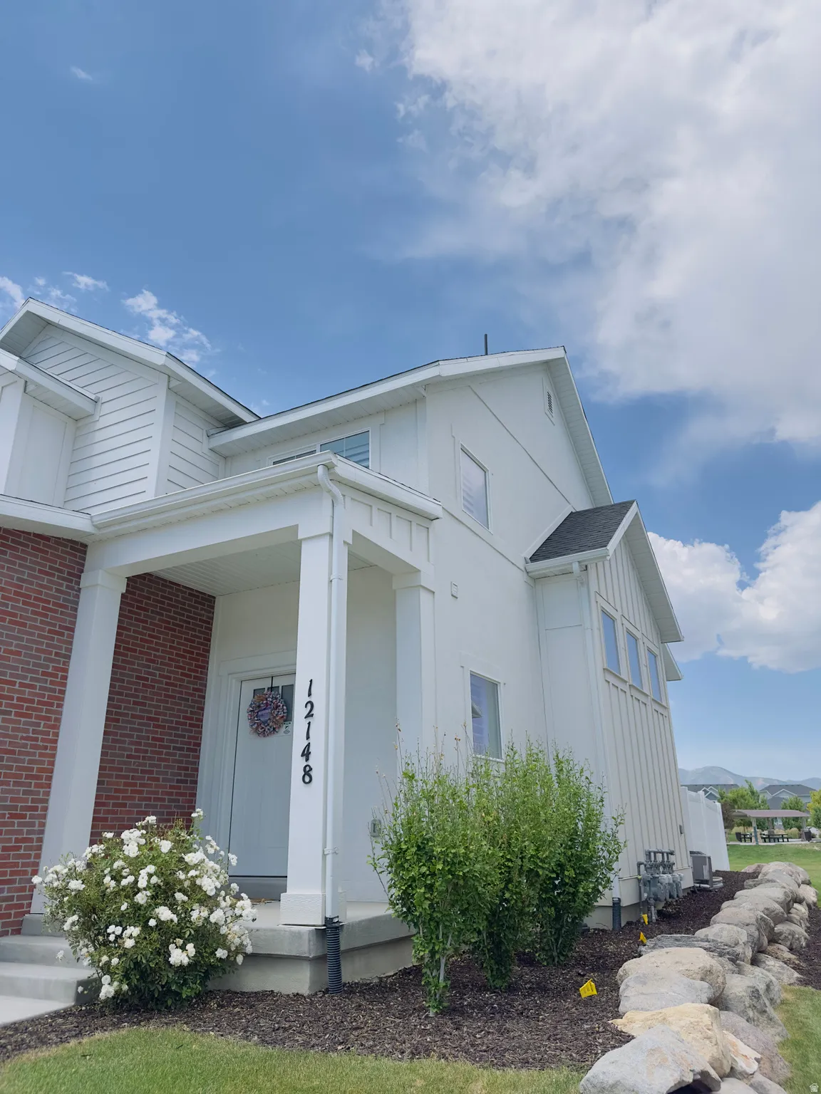 White exterior with brick accents and a covered entry