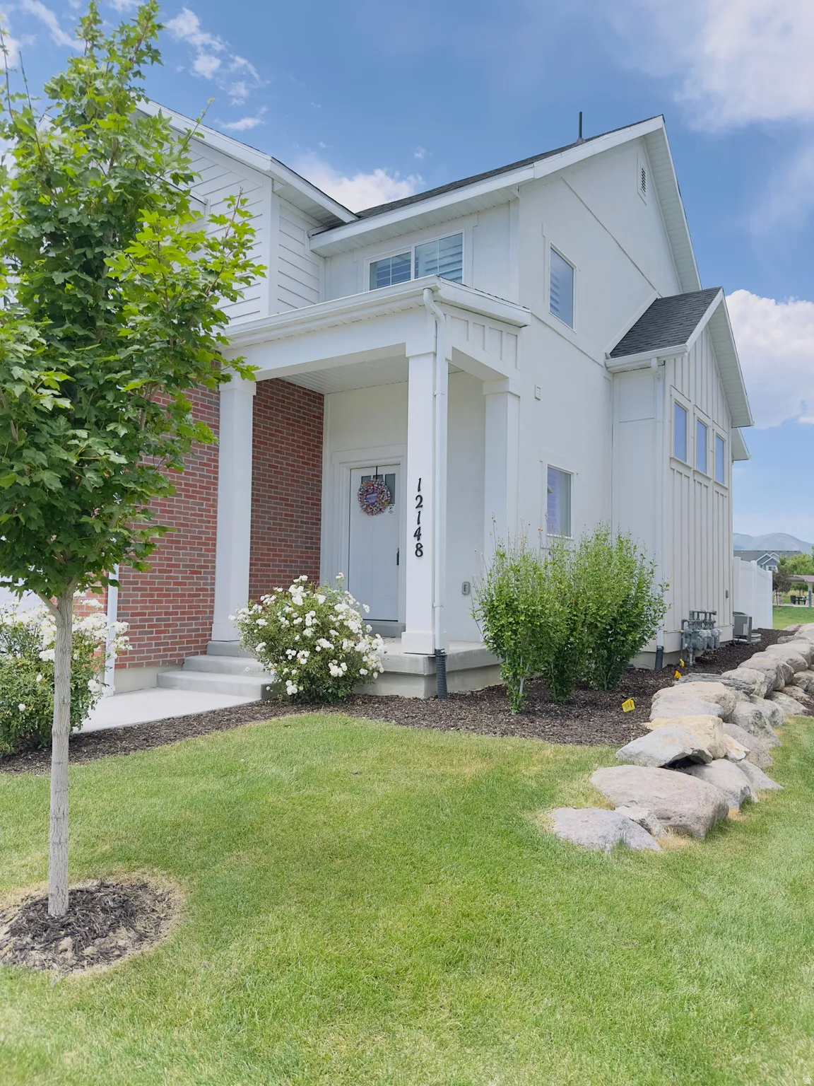 Contemporary facade featuring white siding with brick accents and a covered entry