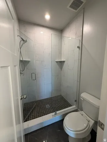 Glass-enclosed shower with a handheld showerhead and built-in shelving