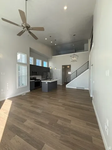 Wood-finish flooring, high ceilings with recessed lighting, and a contemporary ceiling fan