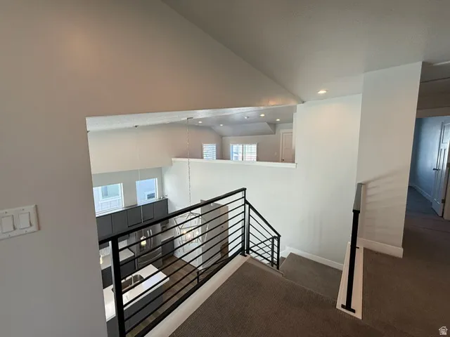 Two-story living area with high ceilings, contemporary horizontal bar railing, recessed lighting, and wood-finish flooring