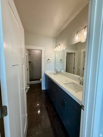 Dual vanity with undermount sinks, stone countertops, and dark blue cabinetry