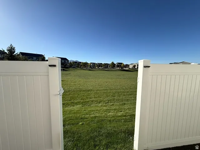 White vinyl fencing with a gate opening to an expansive grass area