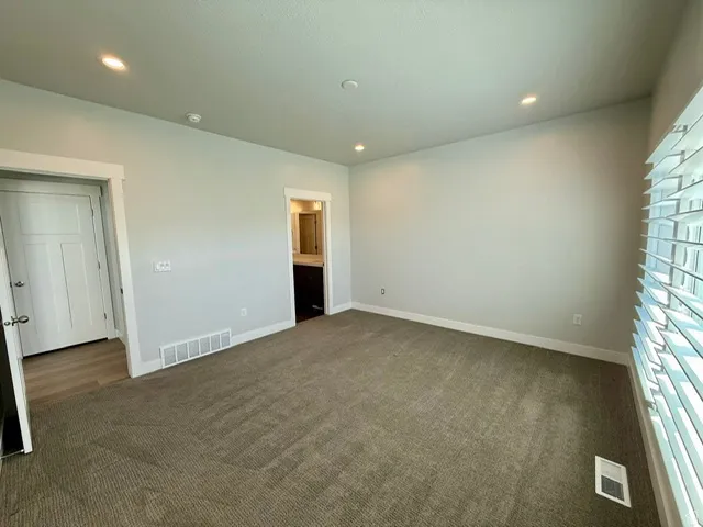 Recessed lighting, light gray wall paint, white trim, window with louvered blinds, and brown carpet flooring
