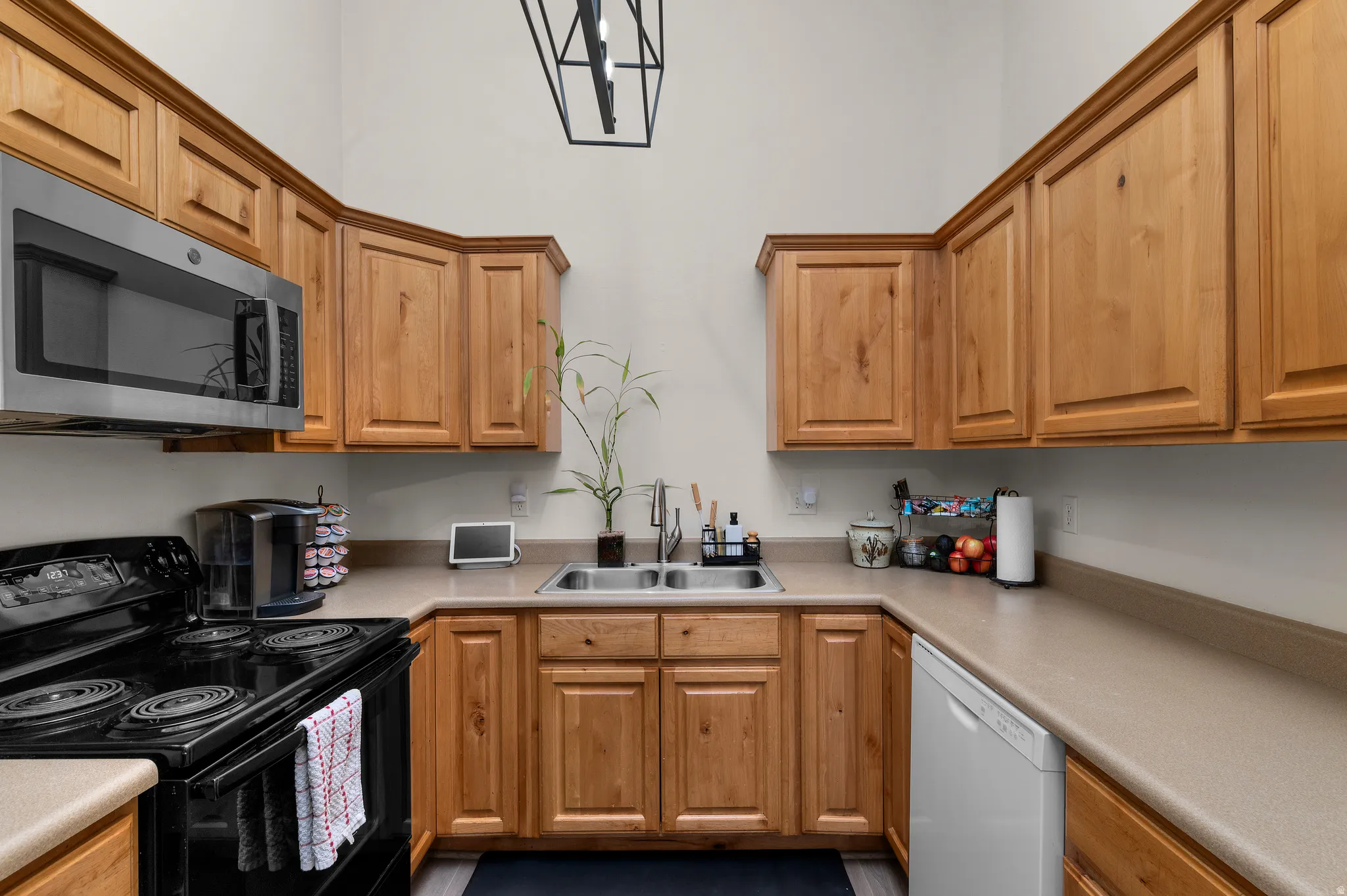 Kitchen featuring natural wood-finish cabinetry, light-toned countertops, and a double basin sink with a chrome faucet