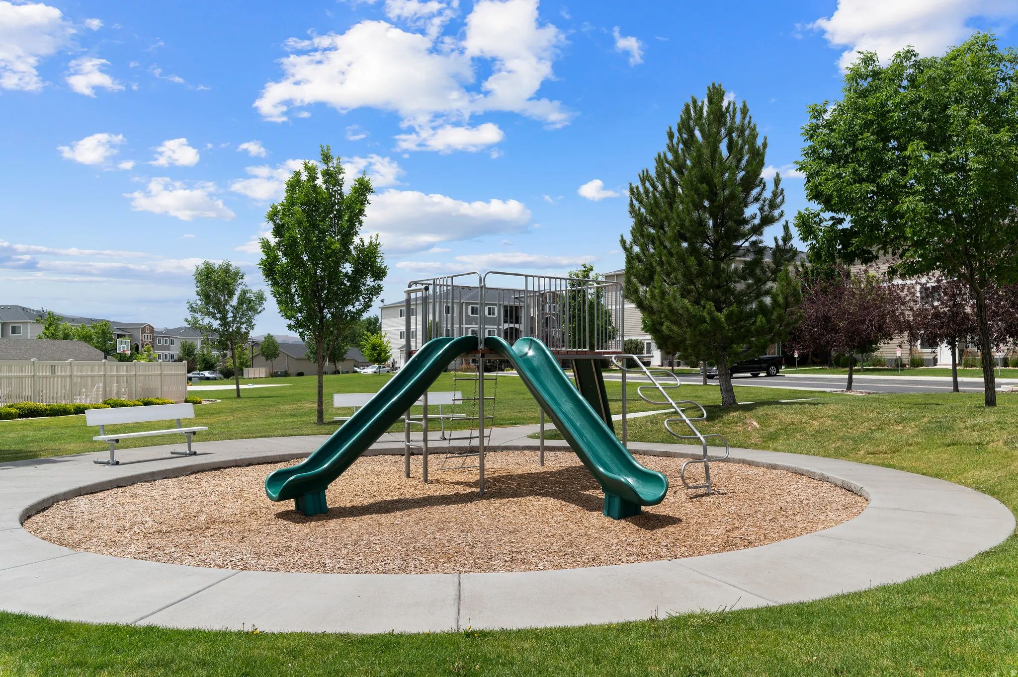 Community playground featuring two green slides and a climbing structure
