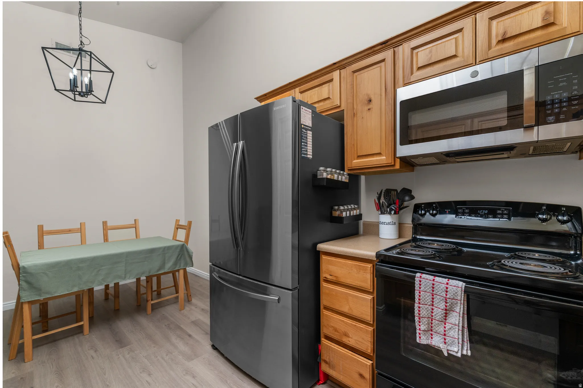 Modern kitchen featuring wood-finish cabinetry, light-toned countertops, and stainless steel appliances including a refrigerator and over-range microwave